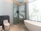 Modern bathroom with freestanding tub, glass shower, and large window