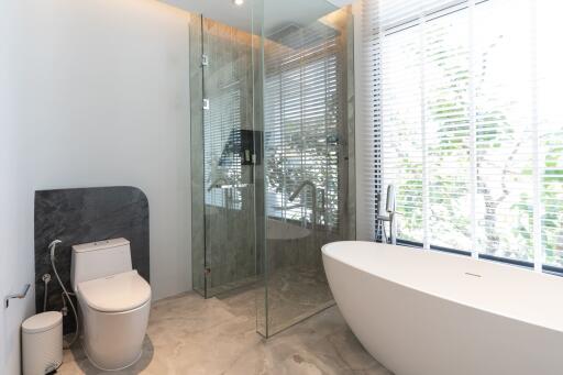 Modern bathroom with freestanding tub, glass shower, and large window