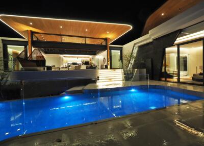 Modern house exterior with illuminated pool at night