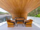 Modern outdoor seating area with wooden ceiling and comfortable chairs