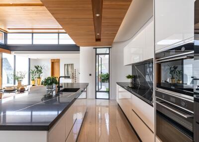 Modern kitchen with island, wooden ceiling, and ample natural light