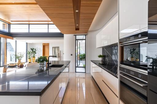 Modern kitchen with island, wooden ceiling, and ample natural light