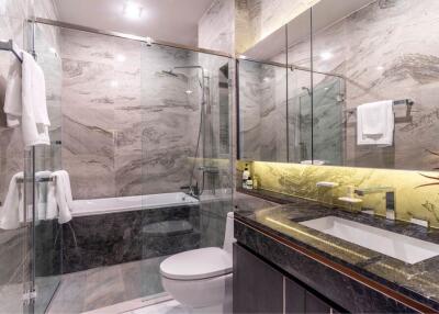 Modern bathroom with glass shower and bathtub, marble tiles, and illuminated mirror