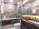 Modern bathroom with glass shower and bathtub, marble tiles, and illuminated mirror