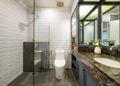 Modern bathroom with glass shower, toilet, and marble countertop