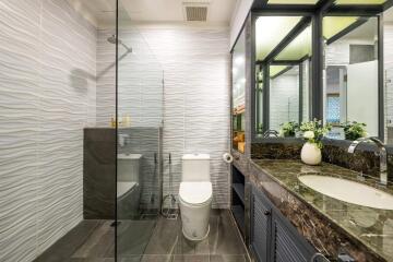 Modern bathroom with glass shower, toilet, and marble countertop