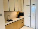 Modern kitchen with minimalist design featuring white cabinetry and wooden lower cabinets