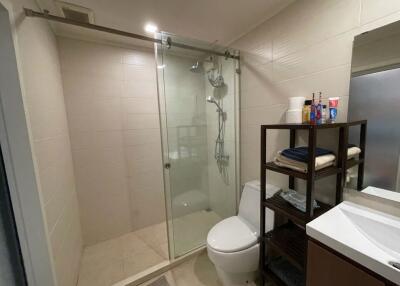 Modern bathroom with glass shower, white toilet, sink, and storage shelving