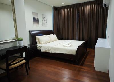 Well-lit bedroom with wooden flooring and modern furniture