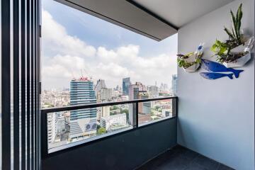 City view from the balcony with decorative wall plants and clear railing