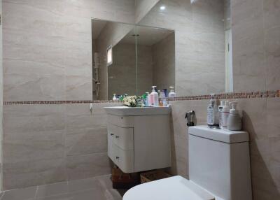 Modern bathroom with a sink, toilet, and large mirror