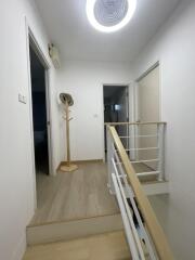 Well-lit hallway with wooden flooring and coat stand