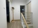 Well-lit hallway with wooden flooring and coat stand