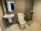 Modern bathroom with a glass-enclosed shower, toilet, and sink