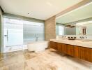 Modern bathroom with a bathtub, large mirror, wooden cabinetry, marble flooring, and large windows with blinds