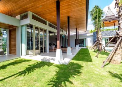 Modern exterior of a luxury home with large windows, wooden ceiling, and landscaped garden.