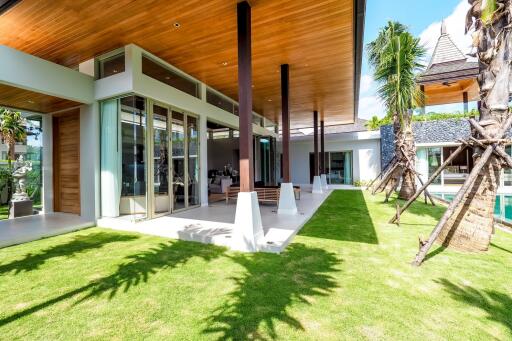 Modern exterior of a luxury home with large windows, wooden ceiling, and landscaped garden.