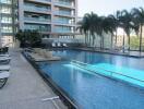 Outdoor swimming pool area with lounge chairs and palm trees