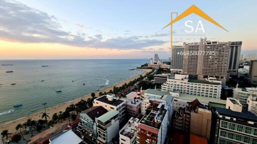 Aerial view of coastal city with beach and high-rise buildings during sunset