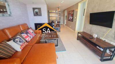 Living room with orange sofa, wall-mounted TV, and decorative items