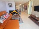 Living room with orange sofa, wall-mounted TV, and decorative items