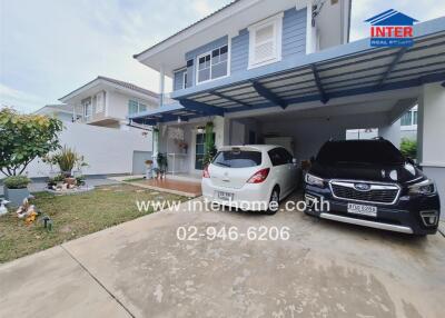 Driveway and front exterior of a residential building with two cars parked under a canopy.