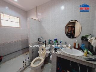 Bathroom with light-colored tiles and various toiletries