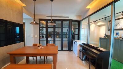 Dining area with wooden table and bench, adjacent glass door and piano