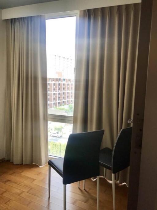 Curtained window in a bedroom with two chairs