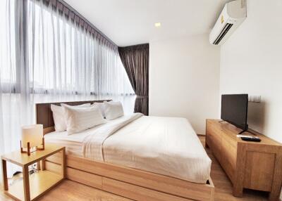 Modern bedroom with a large window, double bed, side table, and TV on a wooden stand