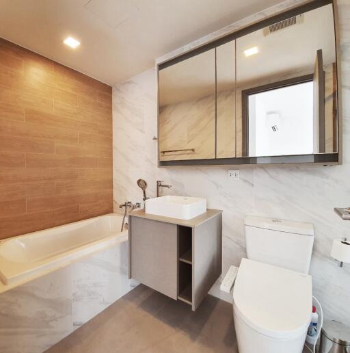 Modern bathroom with bathtub, toilet, and sink.