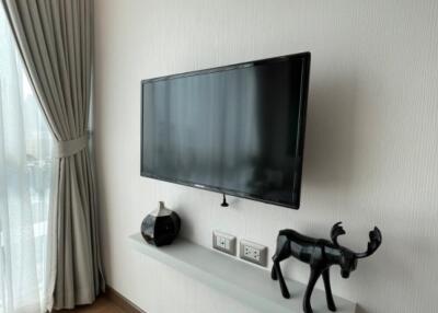 Living room with wall-mounted TV, floating shelf, and curtains