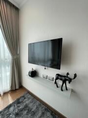 Living room with wall-mounted TV, floating shelf, and curtains