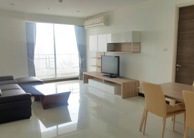 Modern living room with sofa, TV, dining area, and large window