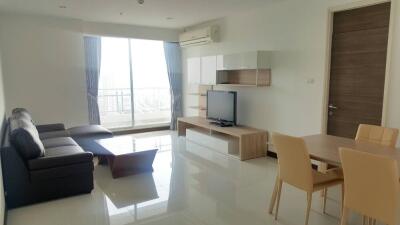 Modern living room with sofa, TV, dining area, and large window