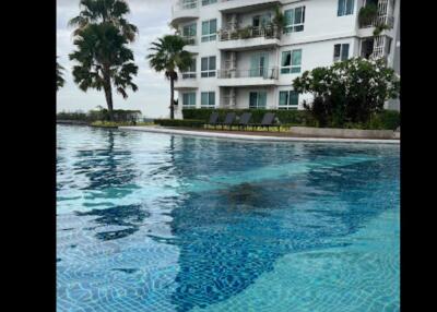 Outdoor swimming pool beside multi-story residential building with balconies