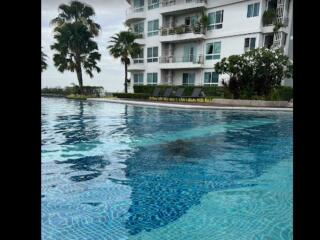 Outdoor swimming pool beside multi-story residential building with balconies