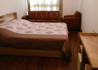 Bedroom with bed, sofa, and wooden flooring