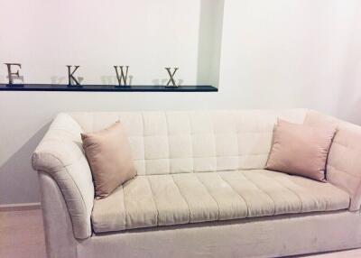 Modern living room with a light beige couch and decorative alphabet letters on a shelf