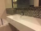 Modern bathroom with mosaic tile backsplash and white sink