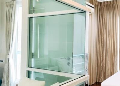 Modern bedroom with glass partition and wooden flooring