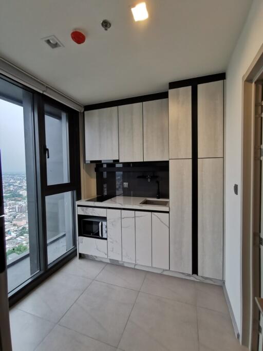 Modern kitchen with large windows, fitted cabinets, and appliances