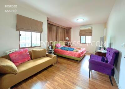 Spacious bedroom with wooden flooring, double bed, sofa, and armchair