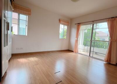 Bright living room with wooden flooring and ample natural light from large windows and sliding door