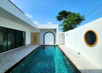 Modern outdoor pool area with clear blue water, white walls, and a unique circular window.