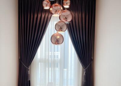 Modern chandelier with globe lights above a stairway with dark curtains