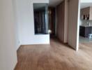 Living area with wooden flooring and partial kitchen view