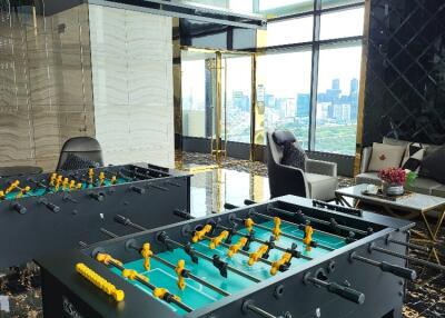 Spacious living area with floor-to-ceiling windows and foosball table