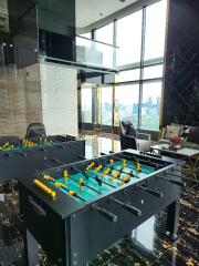 Spacious living area with floor-to-ceiling windows and foosball table