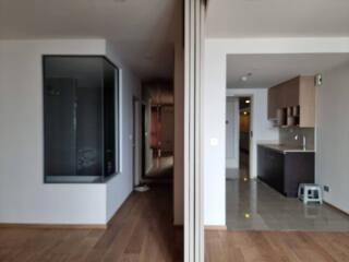 Open concept living space with wooden and tiled flooring, large windows, and a view into the kitchen